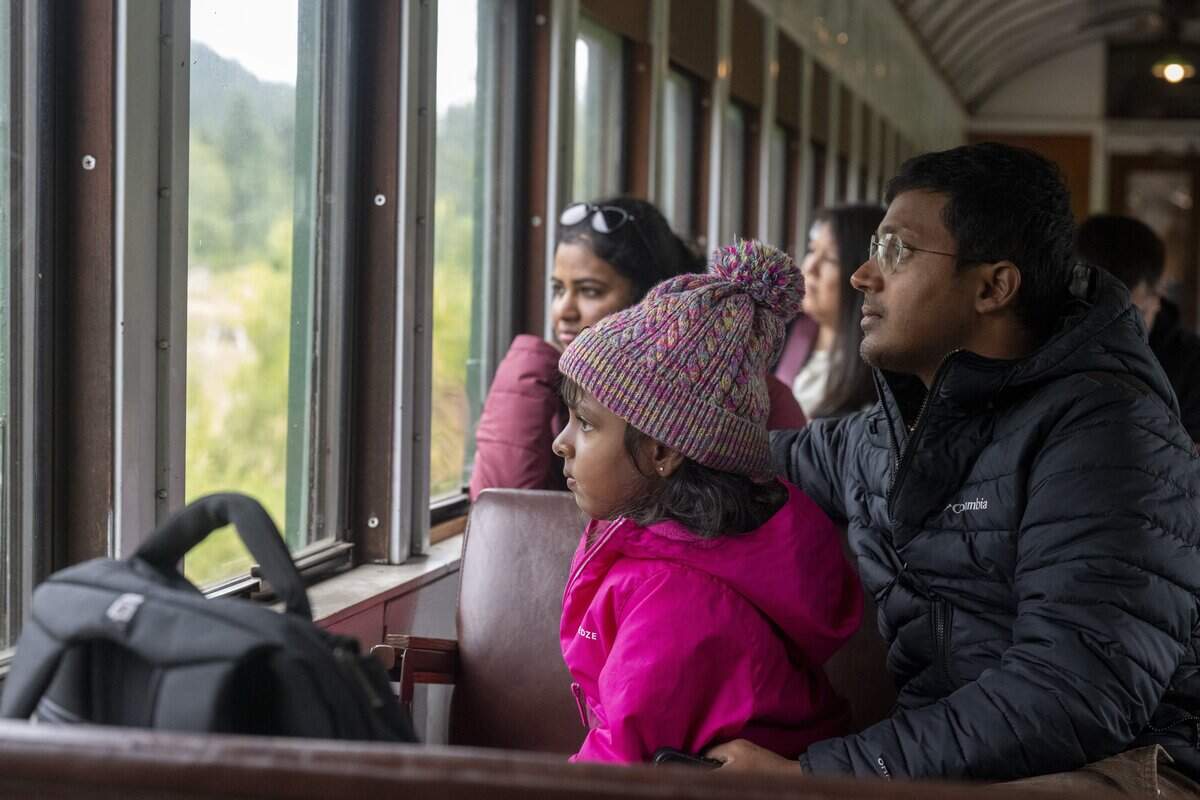 Poovitha Pranesh, left, Aadhini Pranesh, 5, and Pranesh Venkat, right, watch the scenery move by on the Mt. Rainier Scenic Railroad on Thursday, July 16, 2026, after departing from Elbe, Wash. The family from Austin, Texas, are visiting the Mount Rainier area.