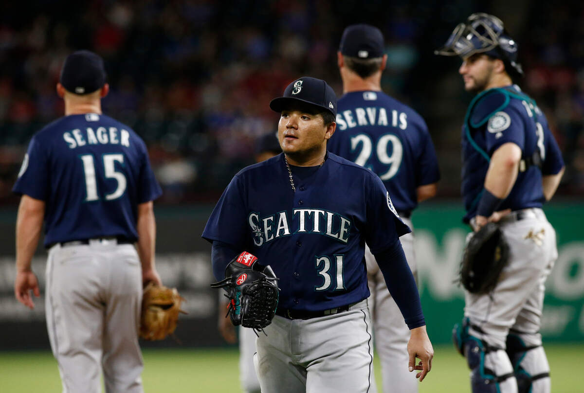 Seattle Mariners starting pitcher Erasmo Ramirez (31) leaves a baseball game against the Texas Rangers as third baseman Kyle Seager (15), manager Scott Servais and catcher Mike Zunino wait on the mound during the third inning of a baseball game Friday, Sept. 21, 2018, in Arlington, Texas. (AP Photo/Mike Stone)