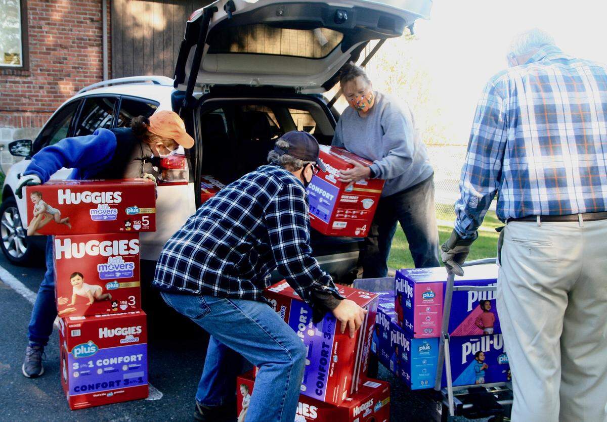 From left, Gig Harbor Kiwanis Club members Pat Riley and Bob Maynard, KPCS Executive Director Willow Eaton, and Kiwanis member Jeff Waters tackle a load of Huggies diapers donated by Eastside Baby Corner–West Sound for use by KPCS clients.