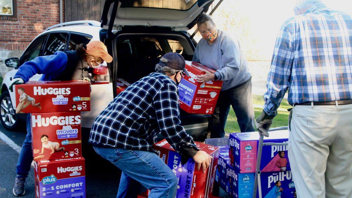 From left, Gig Harbor Kiwanis Club members Pat Riley and Bob Maynard, KPCS Executive Director Willow Eaton, and Kiwanis member Jeff Waters tackle a load of Huggies diapers donated by Eastside Baby Corner–West Sound for use by KPCS clients.