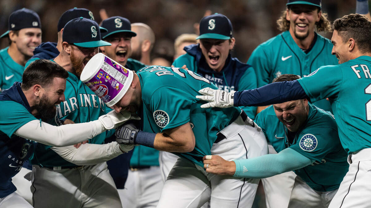 Seattle Mariners including Jesse Winker, left; Ty France, third from right; Logan Gilbert, second from right; and Adam Frazier, right celebrate a home run by Cal Raleigh in ninth inning of a baseball game against the Oakland Athletics, Friday, Sept. 30, 2022, in Seattle. The Mariners won 2-1 to clinch a spot in the playoffs. (AP Photo/Stephen Brashear)
