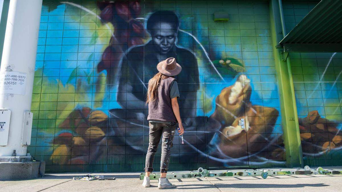 Artist Mari Shibuya contemplates her mural of Carmen Mueses, a cocoa farmer in the Dominican Republic, outside Central Co-op in Tacoma, Wash. The project was commissioned by Fairtrade America in 2021.