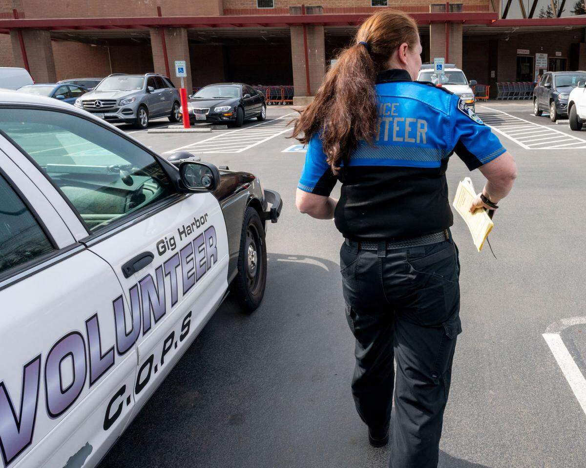 With her ticket book in hand, Gig Harbor Police Department volunteer, Kim Crowder, prepares to give a local parking lot a good once-over to see if any vehicles are illegally parked in disabled spots on Wednesday, April 6, 2022, in Gig Harbor, Wash. 
