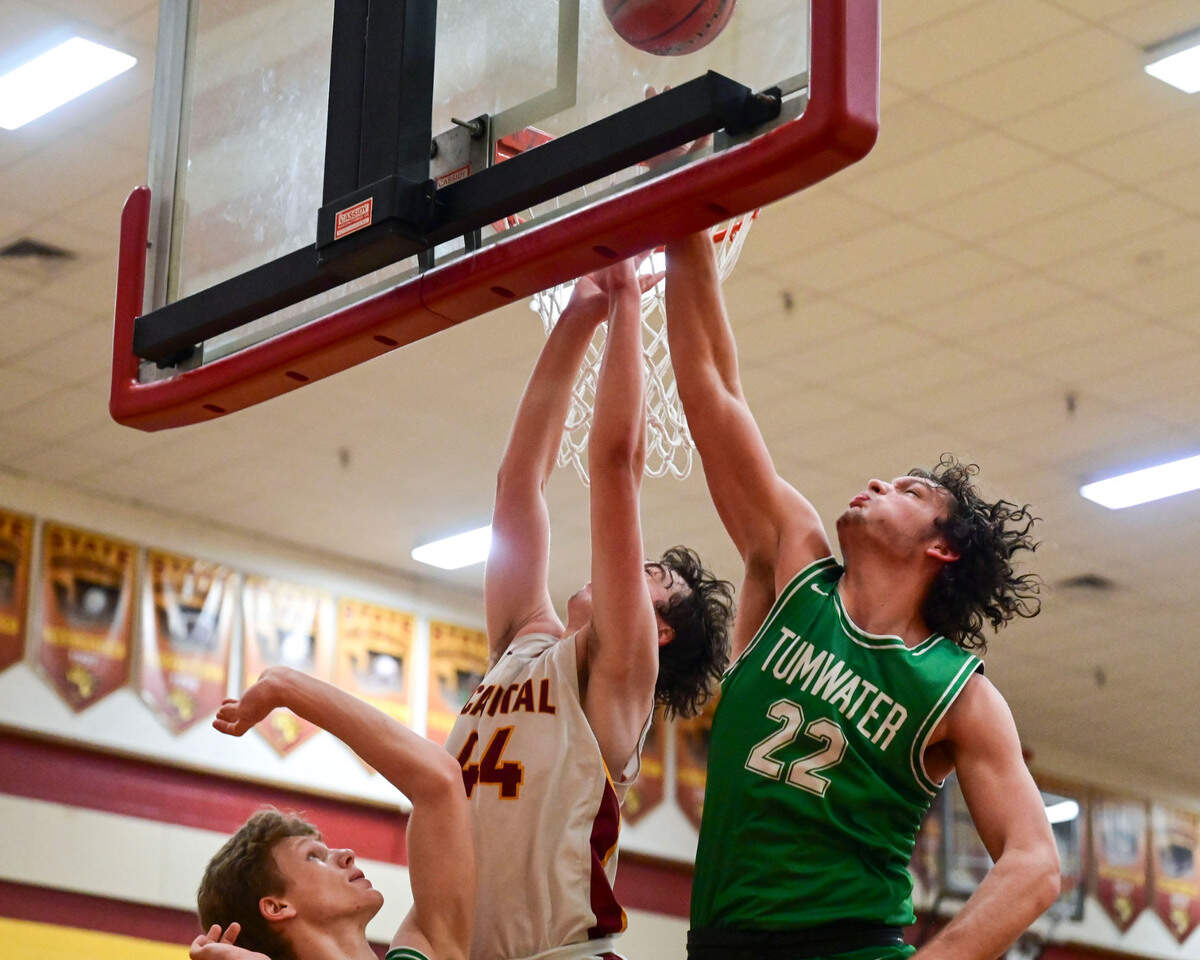 Capital forward Rylan Hill (44) attempts a shot as Tumwater forward Ryan Otton (22) and forward Adam Overbay (32) defend during the third quarter of a non-league game in Olympia on Saturday, Jan. 22, 2022.