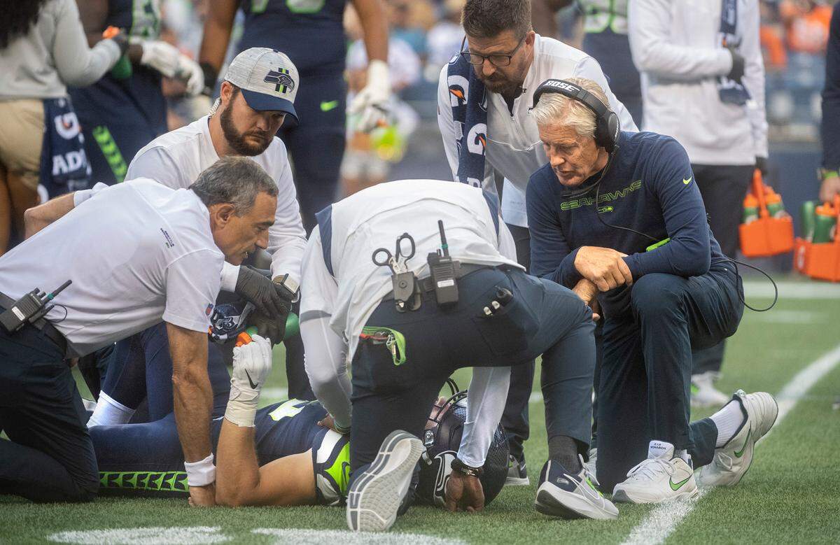 Seahawks head coach Pete Carroll checks on offensive guard Ben Burr-Kirven after he was injured on the first play of Saturday night’s NFL preseason football game against the Denver Broncos at Lumen Field in Seattle, Washington, on Saturday, Aug. 21, 2021.