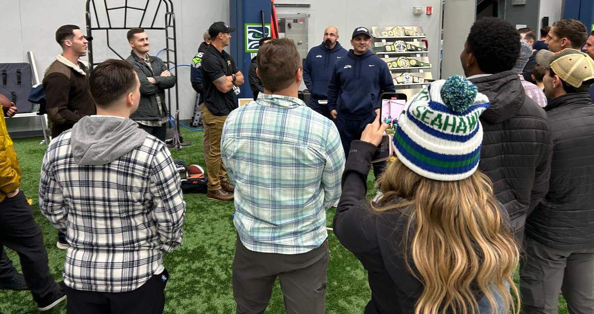 Coach Mike Macdonald (center right, blue team cap) talks to members of a U.S. Army Ranger battalion from Joint Base Lewis-McChord at the Virginia Mason Athletic Center in Renton following Seahawks practice Friday, Nov. 22, 2024.
