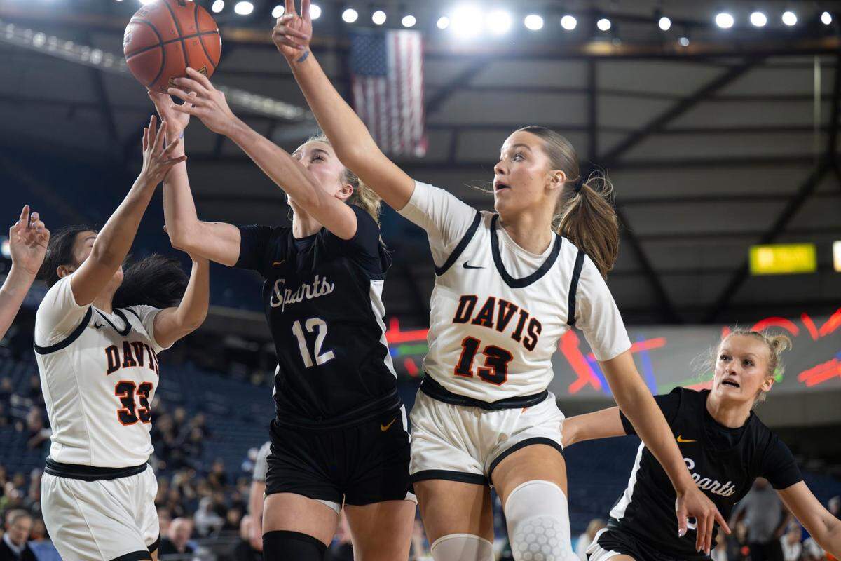 Davis guard Isa Garcia (33) and guard Cheyenne Hull (13) fight for a rebound with Sumner guard Madison Hughes (12) during the first quarter of the Class 4A state championship game at the Tacoma Dome on Saturday, March 8, 2025, in Tacoma, Wash.