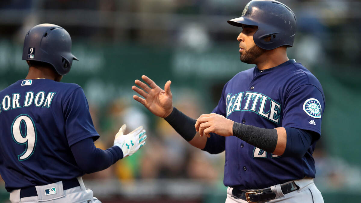 Seattle Mariners’ Nelson Cruz, right, celebrates with Dee Gordon (9) after scoring against the Oakland Athletics during the first inning of a baseball game Thursday, Aug. 30, 2018, in Oakland, Calif. Cruz scored on bases-loaded walk to Ben Gamel. (AP Photo/Ben Margot)