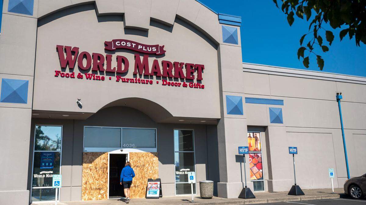 A customer walks toward the entrance of Cost Plus World Market in between a pair boarded up windows that had been recently broken in Tacoma on Tuesday, Sept. 20, 2022. Nine different businesses were broken into on Monday morning in the general vicinity of the World Market.