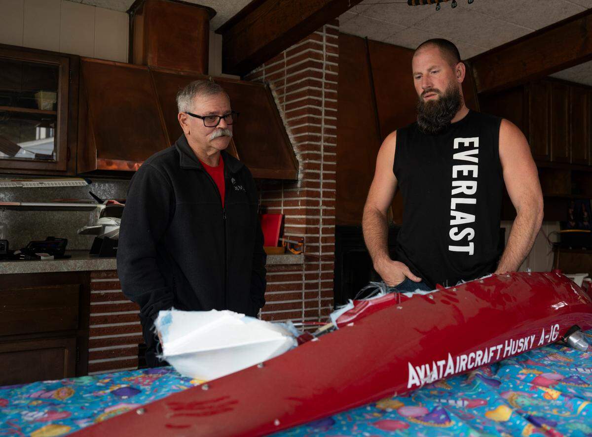 Mark Ceccarelli, left, and Mike Beckett look at the wingtip that was ripped off the plane they crashed in. Photographed at Ceccarelli’s property, on Wednesday, Sept. 11, 2024, in Lakewood.