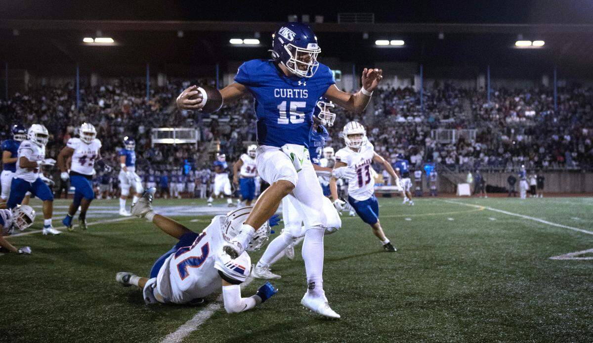 Curtis quarterback Rocco Koch leaps over Graham Kapowsin safety Cohen Miller en route to a 63-yard touchdown run during Friday night’s 4A SPSL football game at Viking Stadium in University Place, Washington, on Oct. 6, 2023. Graham Kapowsin won the game, 42-35.