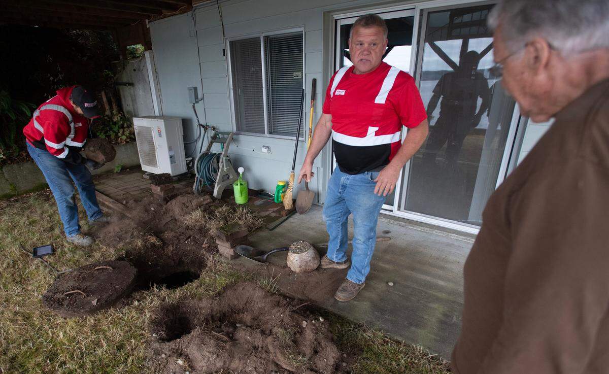 Hemley’s Septic Service owner Jerry Hemley (center) talks with homeowner Dan Van Antwerp as maintenance specialist William Schmidt inspects and cleans out the septic tank at Van Antwerp’s home on the Key Peninsula on Aug. 13.