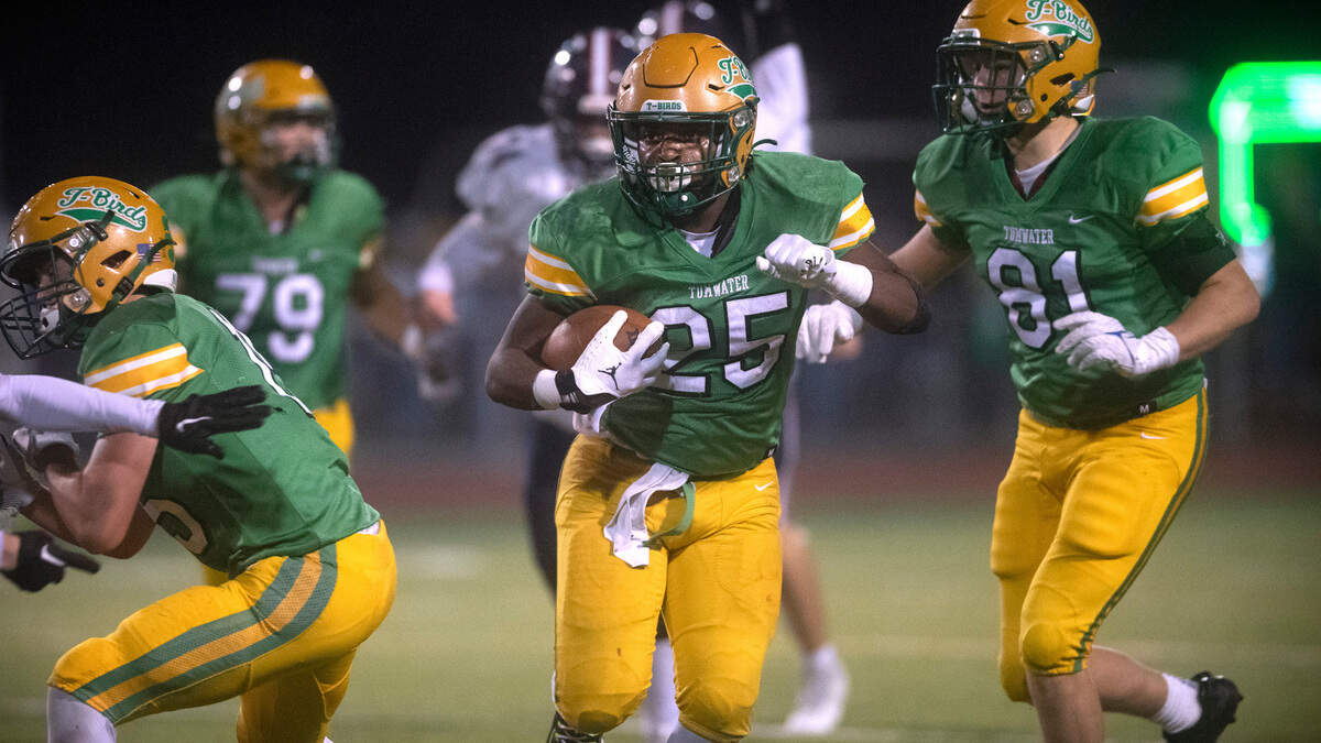 Tumwater running back Carlos Matheney finds running room between blockers Charles Crawford (left) and Beckett Wall during Friday night’s Pioneer Bowl crosstown rivalry football game against the Black Hills Wolves at Tumwater District Stadium in Tumwater, Washington, on Oct. 28, 2022.