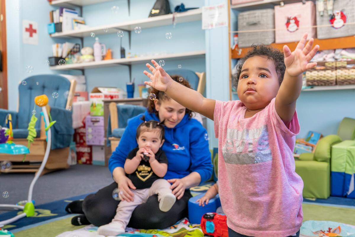 Early Head Start student Josephine, 13 months, right, raises her arms to catch bubbles as they come out of a bubble machine on Friday, May 9, 2025, at the Multicultural Child and Family Hope Center in Tacoma.