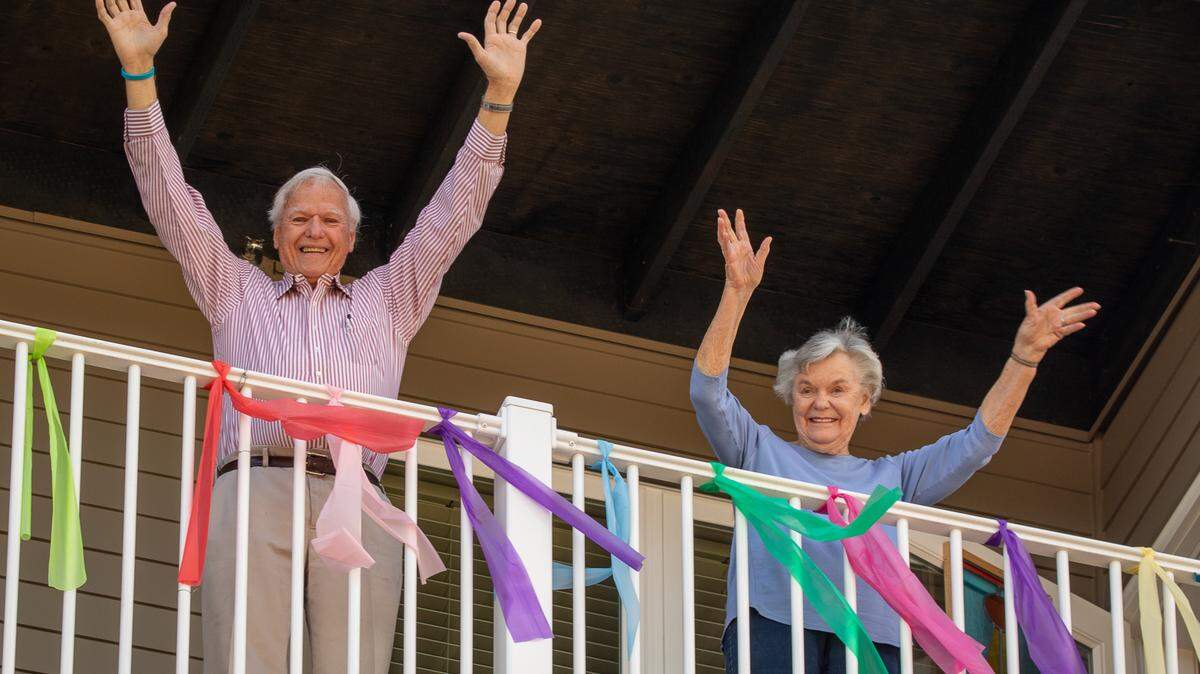 Woody and Betty Holt wave from their “social distancing” balcony, decorated to show appreciation to the staff at Heron’s Key.
