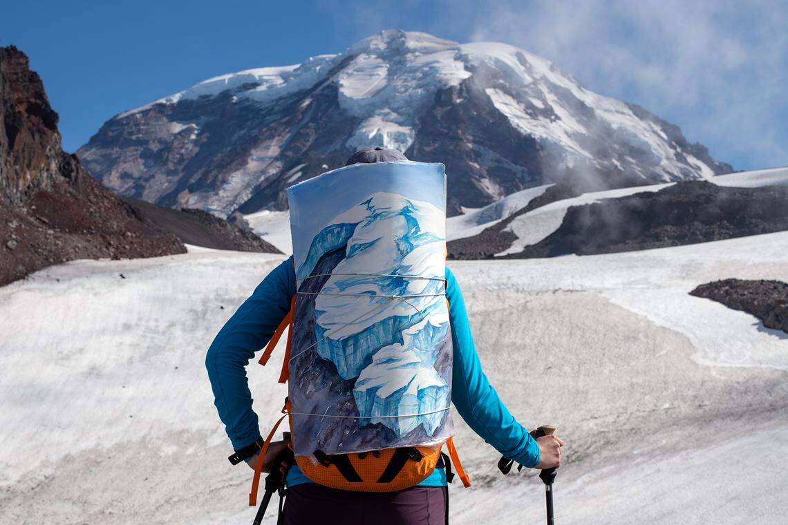 Claire Giordano is pictured hiking on Mount Rainier with one of her glacier artworks strapped to her backpack.