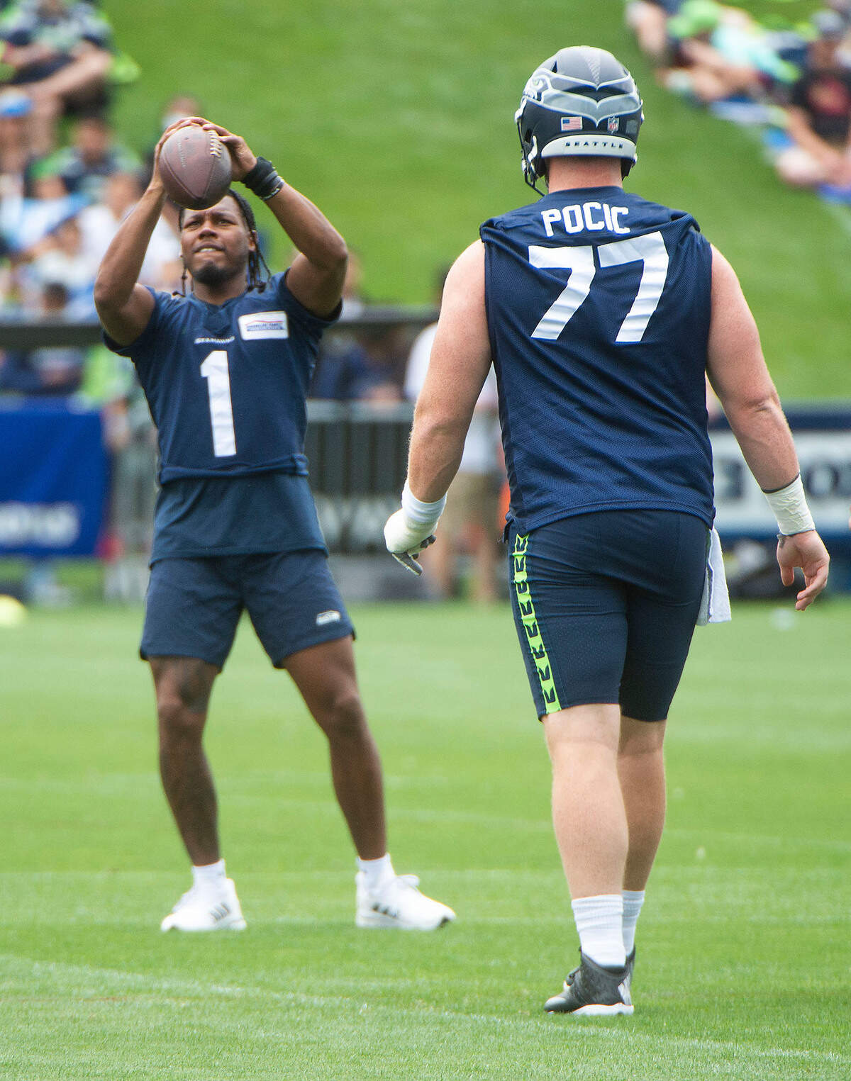 Seattle center Ethan Pocic, walking toward rookie receiver D’Wyane Eskridge, made his first appearance at training camp on Saturday, July 31, 2021 at the VMAC in Renton.