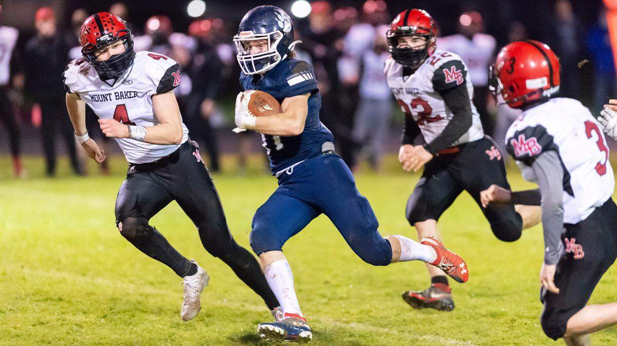 Lynden Christian wide receiver Jackson Apol (31) is chased down by Mount Baker defenders Mason Jacoby (4), left, Jesse Sande (22), and Caleb Horsmon (3) at the end of a long run late in the 3rd quarter on Saturday evening March 20, at Lynden Christian Lyncs. Lynden Christian defeated Mount Baker 33 to 14.