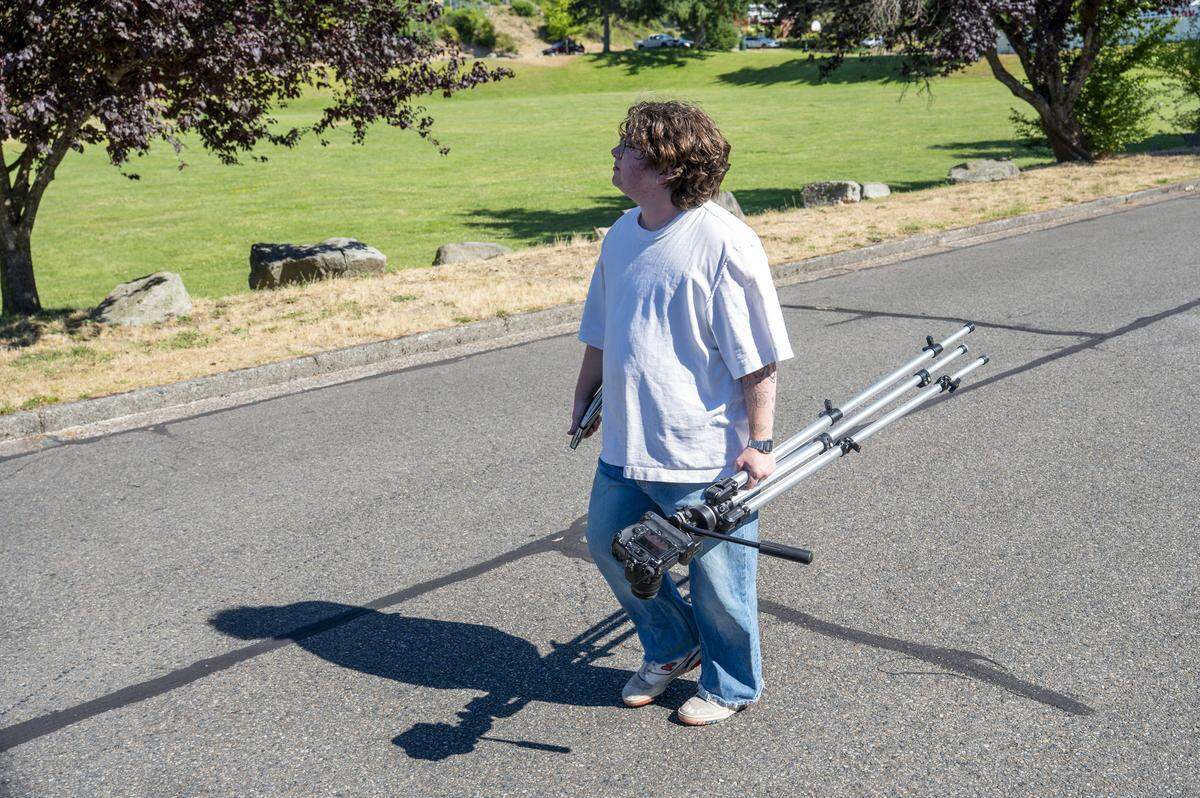 Easton Umansky looks up as he walks between streets to photograph the tree coverage in a neighborhood near Optimist Park on Tuesday, July 15, 2025, in the West End of Tacoma, Wash.
