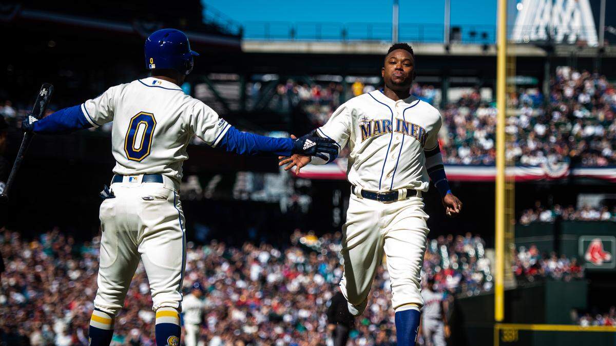 Shortstop Tim Beckham high-fives Mallex Smith (0), at the plate while scoring a run in the third inning. The Seattle Mariners played the Boston Red Sox in a Major League Baseball Game at T-Mobile Park in Seattle, Wash., on Sunday, March 31, 2019.