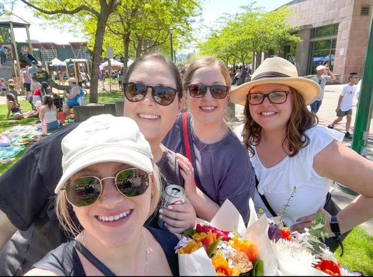 Emily Foster (second from left) visits the Puyallup Farmers’ Market in 2024 with friends and family who she said are big supporters of her new bookshop downtown.