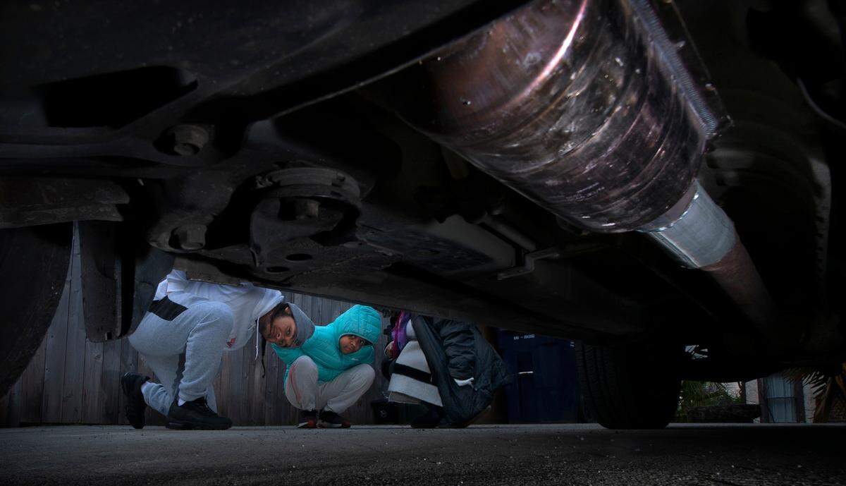 The theft of the catalytic converter from the Conley family’s SUV left Danay Conley without a car and a $1,200 repair bill. “My first thought was ‘Oh no, we’ve been hit!’, said her 17-year-old son, John Conley. “You think it won’t ever happen to you.” John is shown with his sister, Lylah, 10, and mother, Danay Conley, outside their home in Tacoma, Washington, on Tuesday, Feb. 22, 2022.
