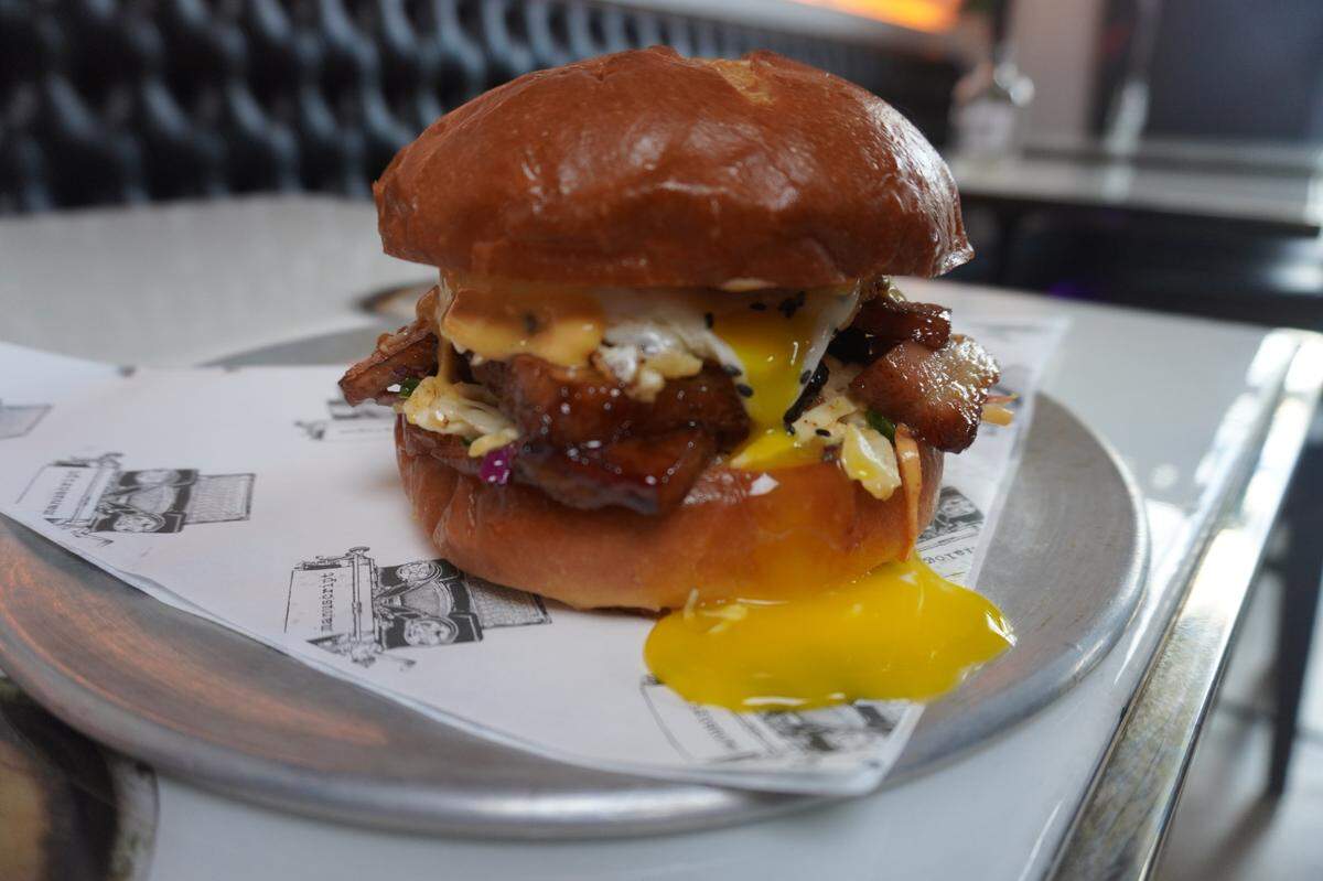 The Eda-Bim Bap sandwich at Manuscript Tacoma features cherry cider-braised pork belly, jalapeno slaw, sriracha aioli and a fried egg on a brioche bun.