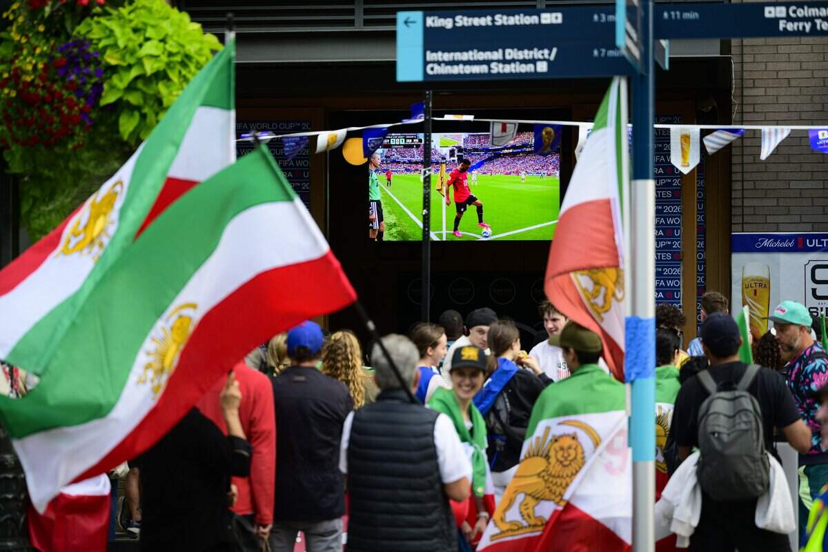 SEATTLE, WASHINGTON - JUNE 26: Soccer fans protesting Iran's current regime wave Iran's Lion and Sun flag outside a bar near Seattle Stadium on June 26, 2026 in Seattle, Washington. The World Cup match between Egypt and Iran was marked by the intersection of traditional soccer fans and those that oppose Iran's current regime. (Photo by Mathieu Lewis-Rolland/Getty Images)