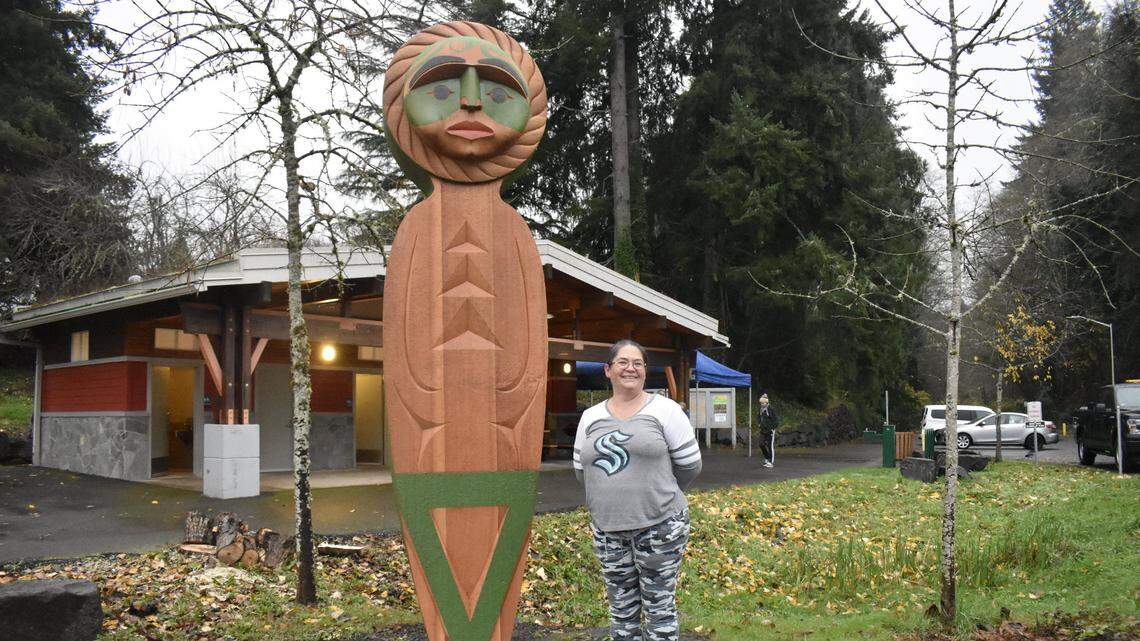 Squaxin Island carver Andrea Wilbur-Sigo stands with one of two 10-foot cedar house posts — carved, painted wooden beams that tell a story and traditionally mark Salish homes — that were installed on either side of the Eastside Street Art Crossing in Olympia, Wash. Members of the Squaxin Island Tribe and Olympia community gathered to celebrate the installation of her piece, named “Unity,” Saturday, Dec. 4, 2021 in Watershed Park. “Unity” is the second of eight public art pieces to be installed at major “gateways” throughout the city.