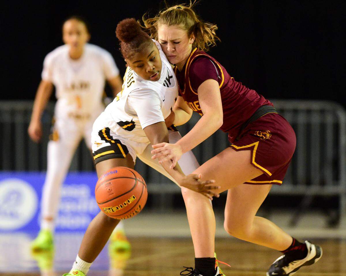 Lincoln guard Malani Warren (24) swipes at the ball while making contact with Lakeside guard Mia Broom (10) during the second quarter of a Class 3A state tournament game on Wednesday, March 2, 2022, at the Tacoma Dome, in Tacoma, Wash.