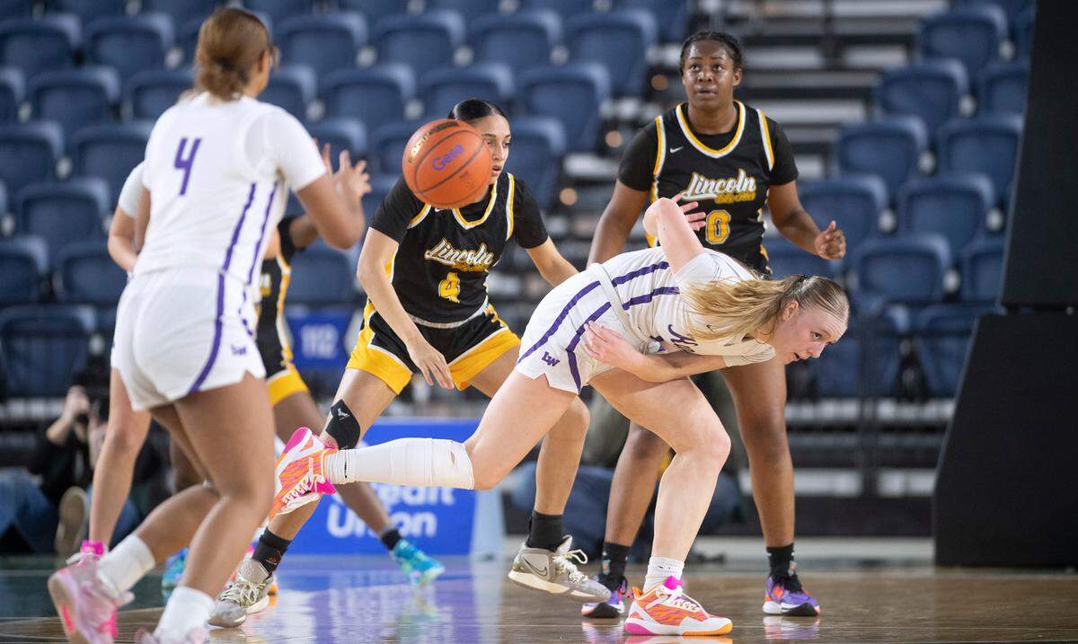 Lake Washington’s Sydney Hani dishes off a pass to teammate Angie Helf under pressure from Lincoln defenders Gianna White (4) and DeAndrea Woods Singleton during their state quarterfinal game at the WIAA state basketball tournament in the Tacoma Dome in Tacoma, Washington, on Wednesday, March 1, 2023. Lake Washington won the game, 57-52.