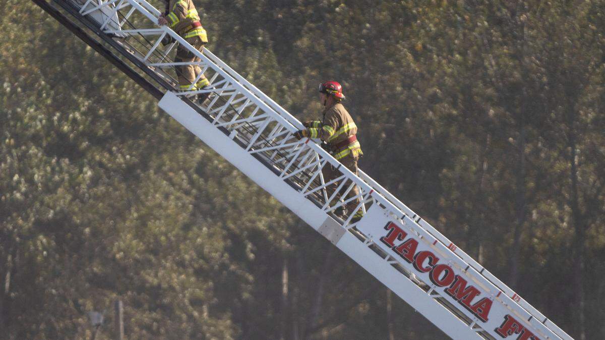 In this Sept. 27, 2022 photo, a pair of firefighters from the Tacoma Fire Department walk up an extended ladder as crews battle a fire at Darling Ingredients on the 2000 block of Marc Avenue near the Port of Tacoma.