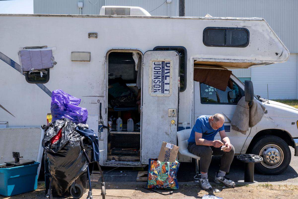 Michael Moehringer sits alongside his RV that he shares with his adult son, Jesse, after they both received treatment from a Greater Lakes Homeless Outreach and Stabilization Team on Tuesday, June 6, 2023, along South Trafton Street in Tacoma, Wash. Jesse Moehringer said that when they lost their house and ended up in the RV it was in very good shape. However, weather and general wear-and-tear has worn the RV down to something almost inoperable.