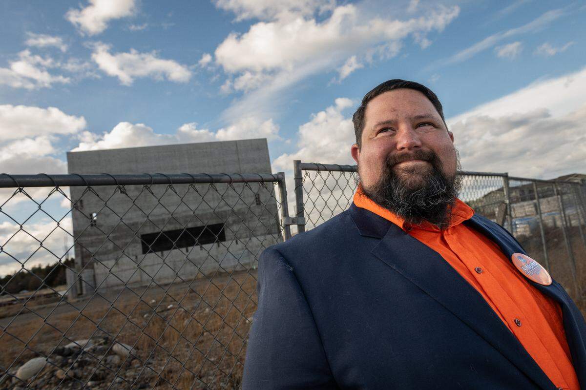 Spokane Valley City Councilmember Al Merkel poses for a photo by the “tombstone”, an unfinished construction project that is scheduled to become The Idaho Central Spokane Valley Performing Arts Center, on Friday, March 14, 2025 in Spokane Valley, Wash. (Erick Doxey for InvestigateWest)