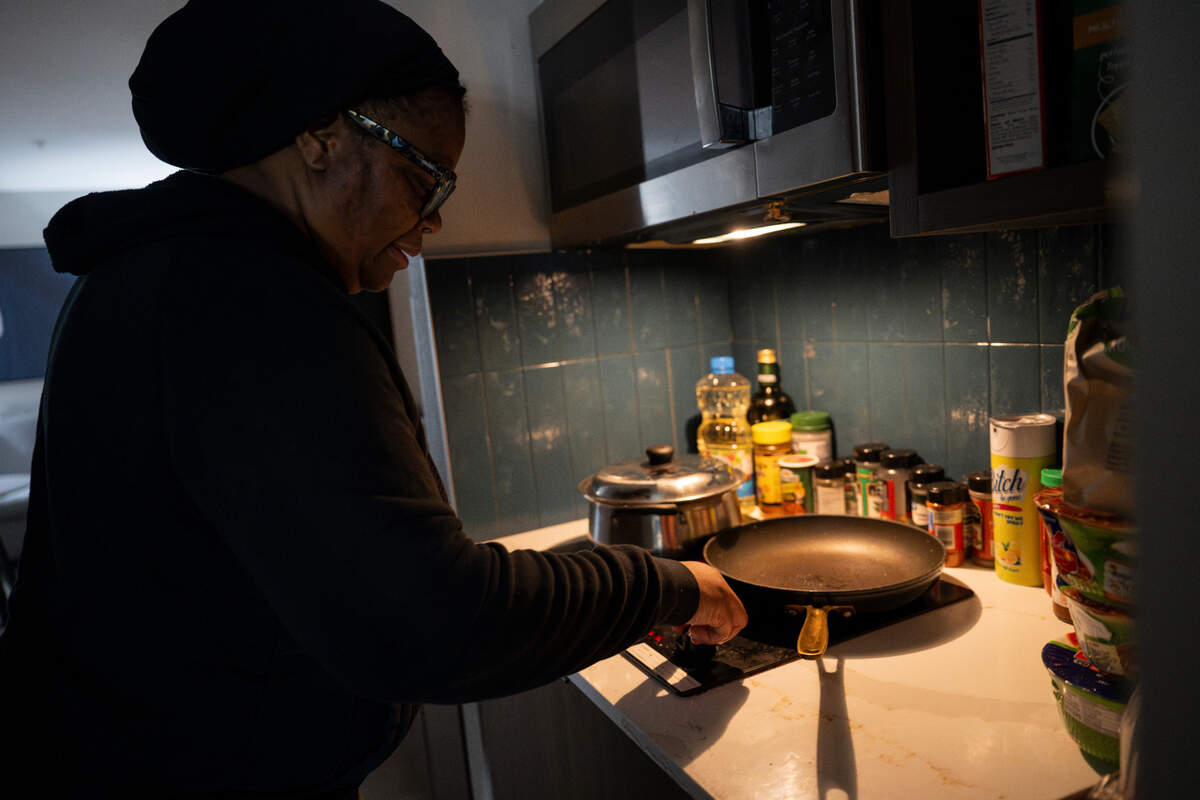 Renee Niles prepares dinner for her family of five on two small burners in their room at Staybridge Suites, on Wednesday, Feb. 7, 2024, in Federal Way, Washington. The Niles family has been living in the hotel for five months, claiming that their insurance company has neglected to remediate water damage and mold in their home in Spanaway.