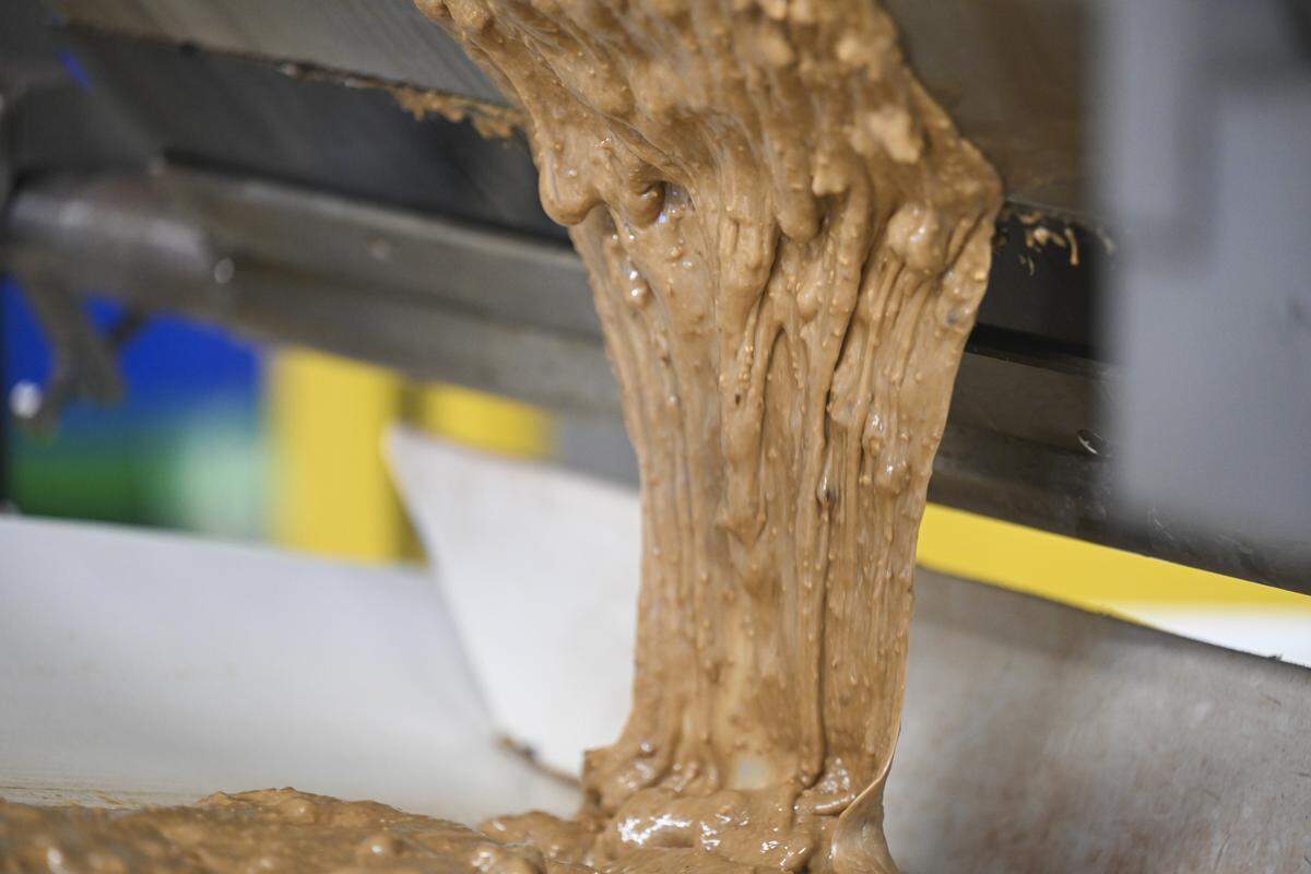 Warm toffee stretches out and cools as it meets a conveyor belt on Tuesday, April 7, 2026, at the Brown & Haley factory in Tacoma, Wash.