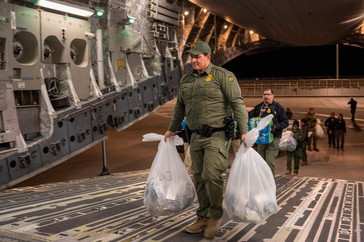 U.S. Customs and Border Protection Agents load water bottles and deportees’ personal belongings onto a C-17 Globemaster III at the Tucson International Airport, Ariz., Jan. 23, 2025. Under the direction of U.S. Northern Command, U.S. Transportation Command is supporting Immigration and Customs Enforcement removal flights by providing military airlift. (Dept. of Defense photo by Senior Airman Devlin Bishop)