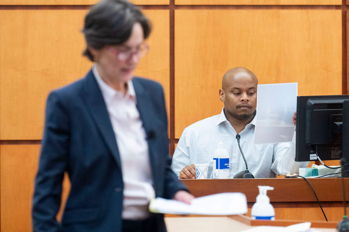 Sedrick Altheimer looks at a picture he took with his cell phone of the SUV Pierce County Sheriff Ed Troyer was following him in while on his paper route on the morning of Jan. 27, 2021, as Washington State Assistant Attorney General Melanie Tratnik walks away from the witness stand on Tuesday, Dec. 6, 2022, in Pierce County District Court in Tacoma, Wash.