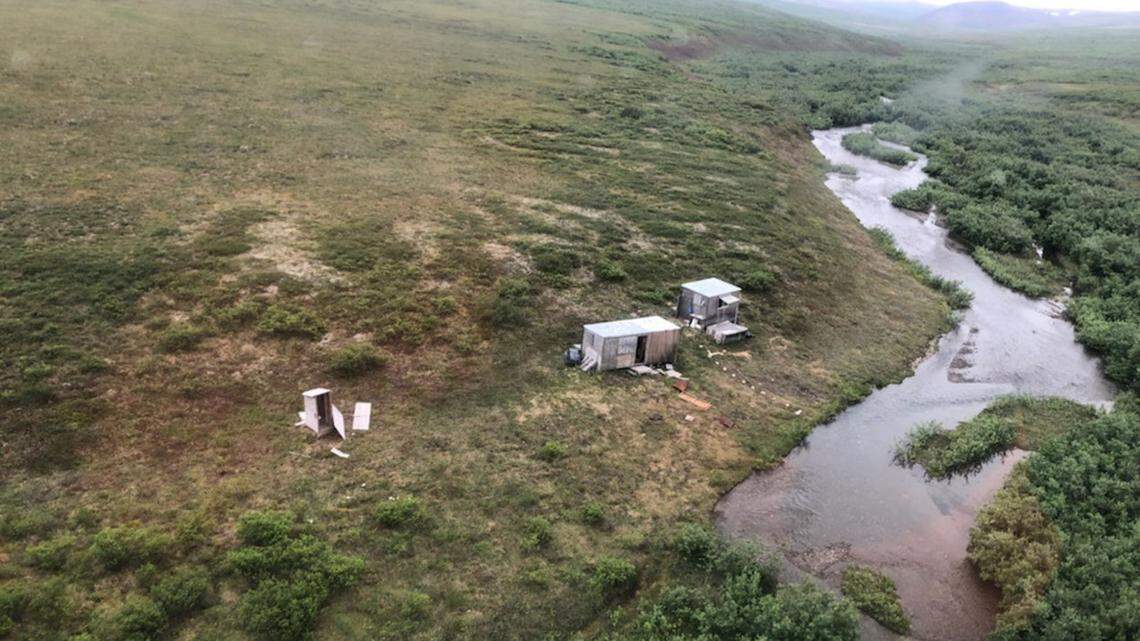 An unidentified man wounded by a bear attack was discovered by Coast Guard in a remote mining camp July 16 in Nome, AK, after he built SOS sign on a shack. By U.S. Coast Guard.