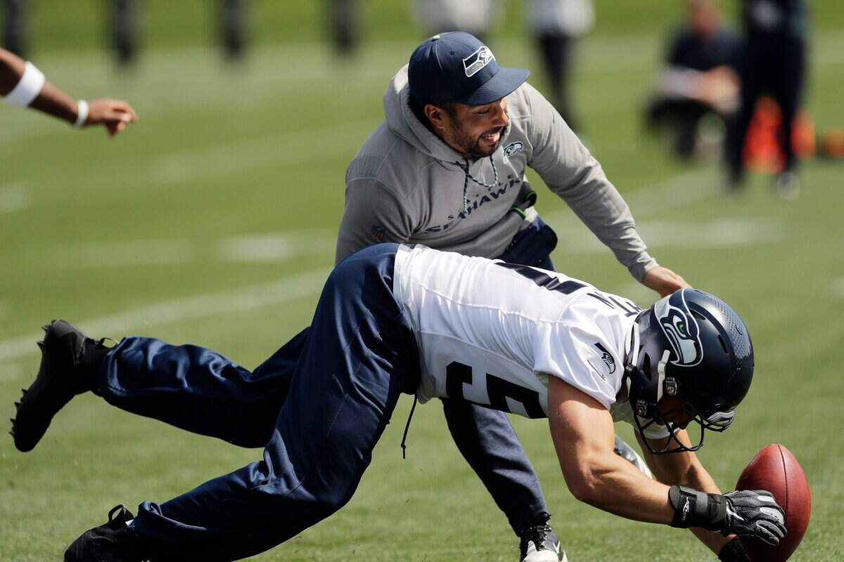 Rookie linebacker Cody Barton, bottom, dives for the ball after it was bobbled by running backs coach Chad Morton during a drill at Seahawks rookie minicamp last month at team headquarters in Renton. Seattle has signed its third-round pick. Barton is the last of 11 draft choices to sign, six weeks before training camp is to begin.