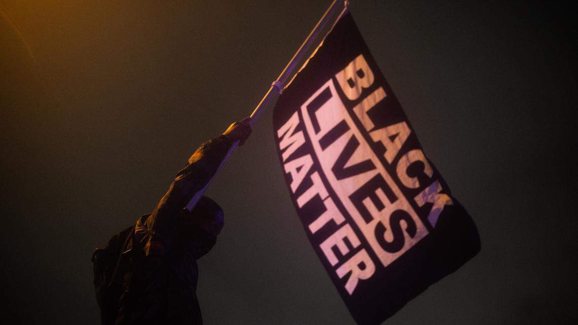 A protester holds a “Black Lives Matter” flag on the on-ramp to I-705 in Tacoma, Wash., on Saturday, May 30, 2020. The protesters were marching against police violence in the wake of the George Floyd killing in Minneapolis.