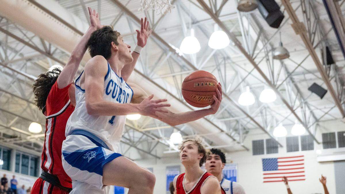 Curtis guard Tyce Paulsen (1) goes up for a reverse lay-in as Camas guard Theo McMillan (20) defends during the first quarter of a District 3/4 semifinal game on Thursday, Feb. 16, 2023, at Curtis High School in University Place, Wash.