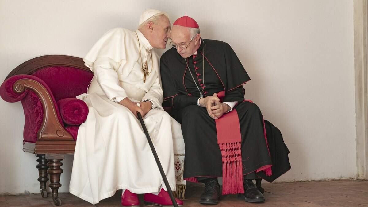 This image released by Netflix shows Jonathan Pryce as Cardinal Bergoglio, right, and Anthony Hopkins as Pope Benedict in a scene from “The Two Popes.”