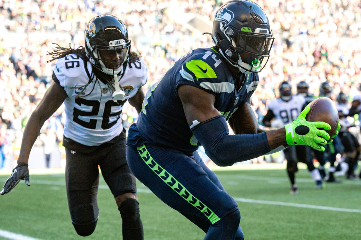 Seattle Seahawks wide receiver DK Metcalf (14) makes a catch in the endzone on a toss from quarterback Geno Smith as Jacksonville Jaguars cornerback Shaquill Griffin (26) defends during the third quarter of an NFL game on Sunday at Lumen Field in Seattle.