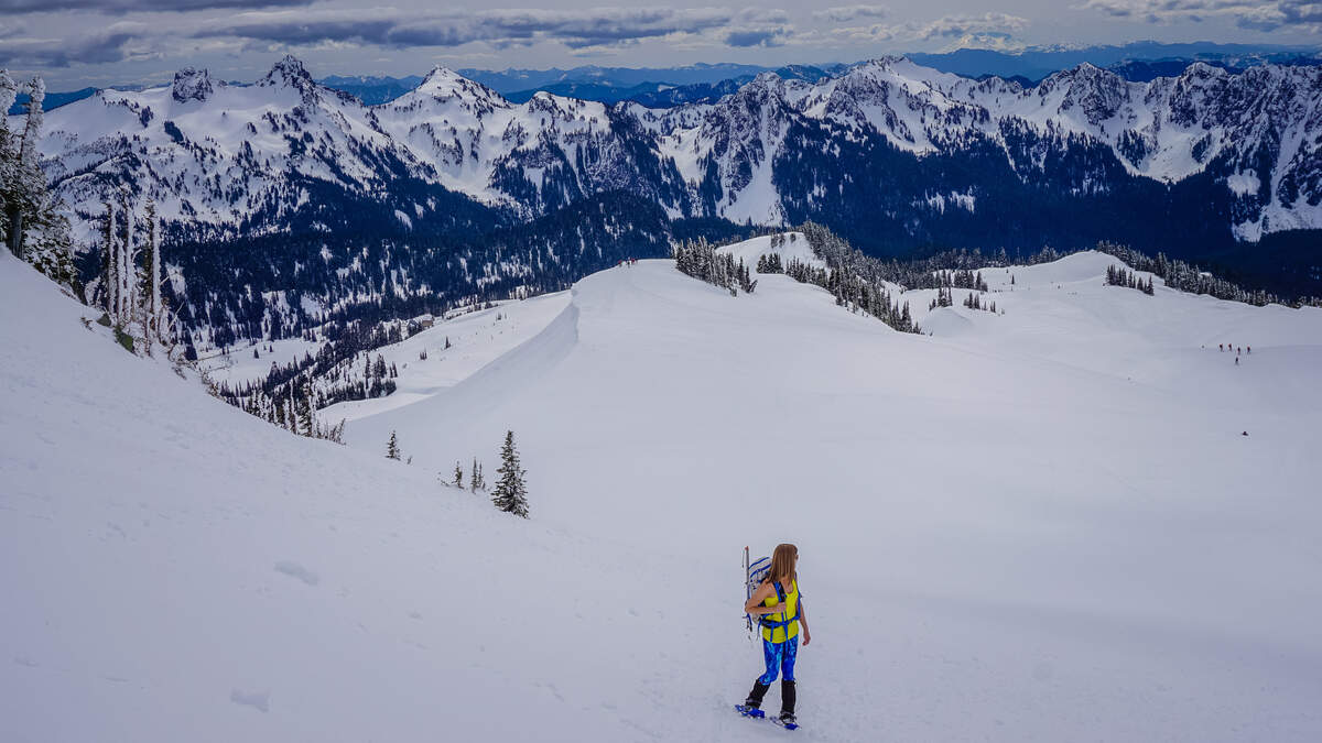 A snowshoer pauses on the way up Panorama Point to look back at the Tattoosh mountain range in Mount Rainier National Park. 