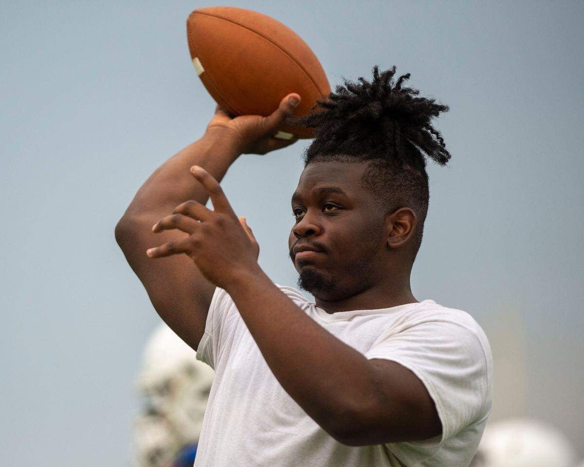 Graham-Kapowsin running back Jalen Davenport, who is recovering from an injury and wasn’t practicing on Thursday, tosses a football with a teammate on Aug. 18, 2022, at Graham Kapowsin High School, in Graham, Wash.