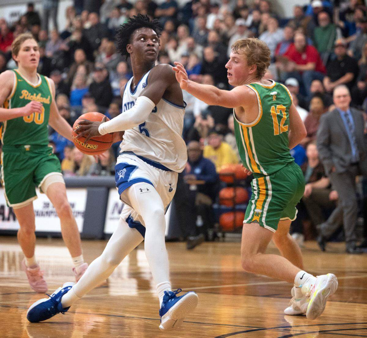 Curtis’ Zoom Diallo drives the lane between Richland defenders Brock Streufert (left) and Josh Woodard during Friday night’s 4A boys state regional playoff game at Tacoma Community College in Tacoma, Washington, on Feb. 24, 2023. Curtis won the game, 64-55.