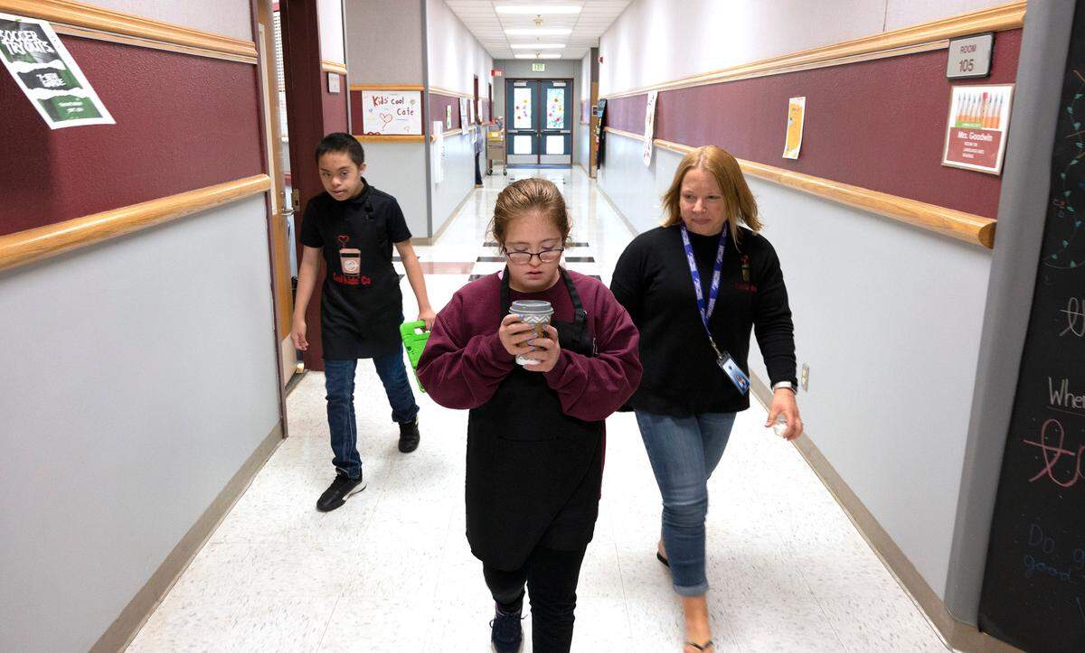 Kate Buerer carefully carries a latte as she and partner Hans Cagabcob and paraeducator Meagan Crum they make a delivery from the Cool Kids Cafe at Goodman Middle School in Gig Harbor, Washington, on Thursday, Sept. 15, 2022.