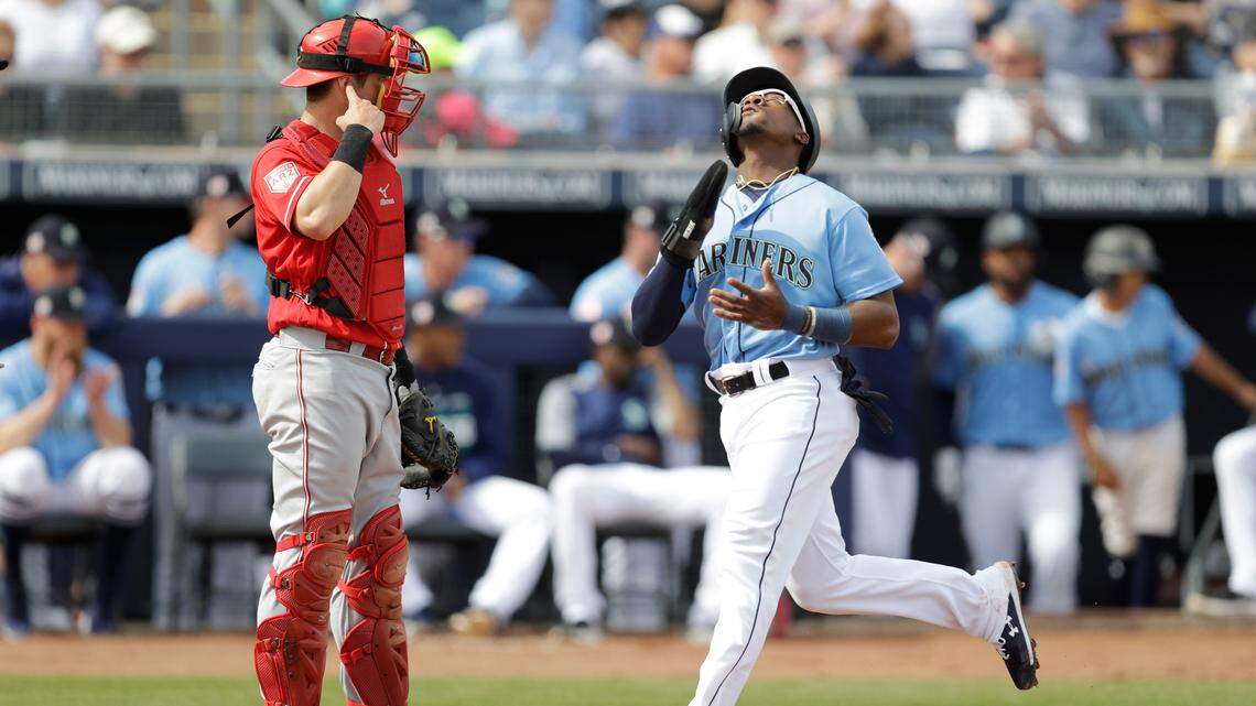 Seattle Mariners’ Shed Long reacts after scoring in front of Cincinnati Reds catcher Chris Okey during the first inning of a spring training baseball game, Monday, Feb. 25, 2019, in Peoria, Ariz. (AP Photo/Darron Cummings)
