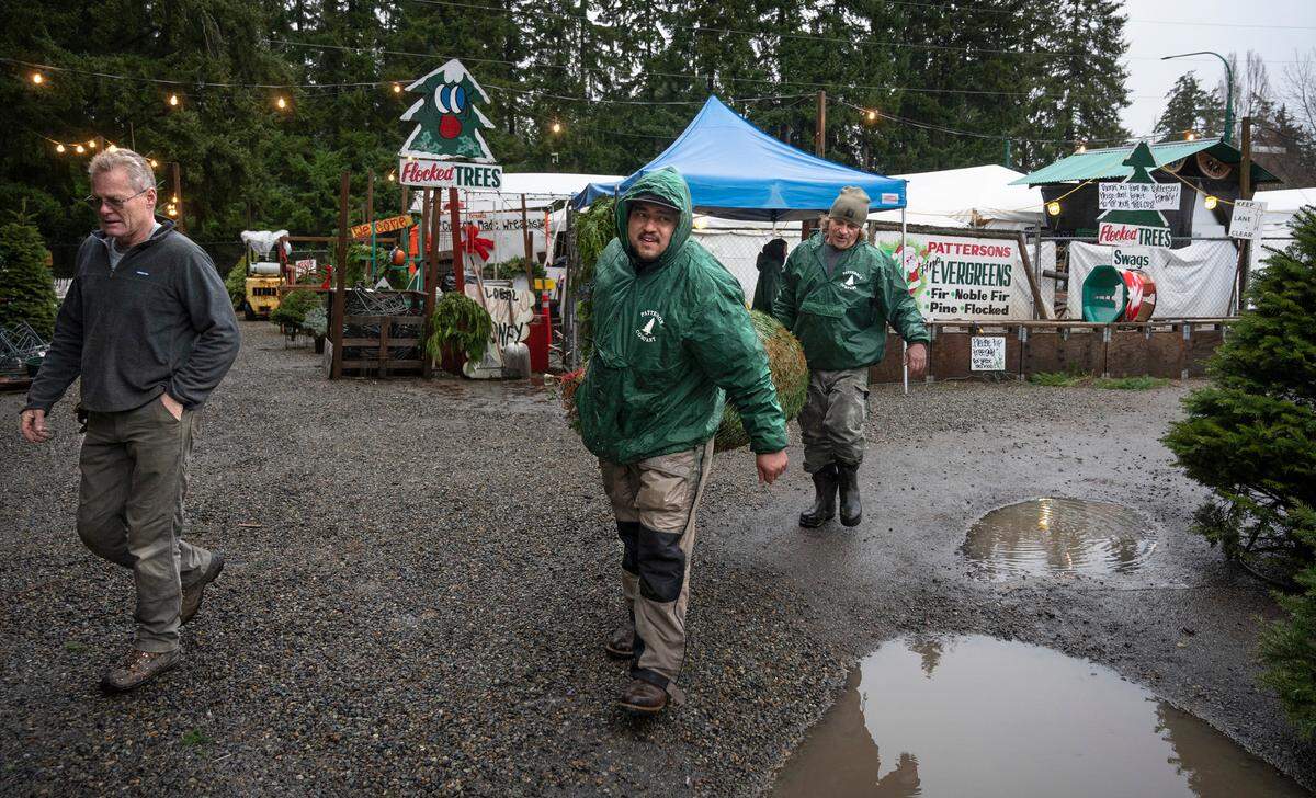 Jordan Boyd (center) and Rick Patterson help Howard Nelson of Gig Harbor with his Christmas tree at Patterson’s Farm Market in Gig Harbor, Washington, on Tuesday, Dec. 20, 2022.